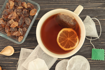 Tea bags and cup with hot beverage on table