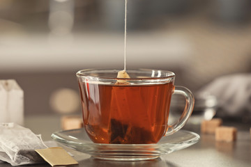 Dipping tea bag into cup on table