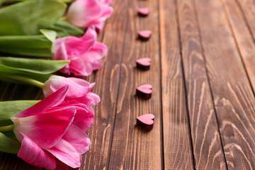 Beautiful tulips and small decorative hearts on wooden background, closeup