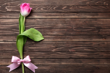Beautiful tulip with ribbon bow on wooden background