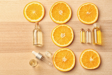 Bottles of essential oil and citrus slices on table, top view
