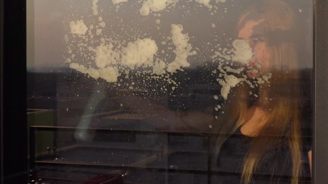 A young beautiful woman cleans a window - closeup