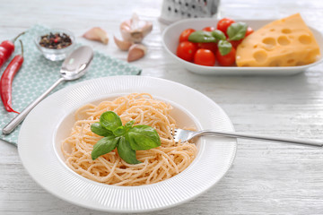 Plate with spaghetti and basil on table. Delicious pasta recipes
