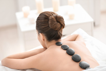 Obraz na płótnie Canvas Young woman enjoying stone massage in spa salon