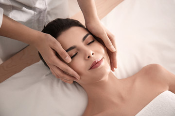 Young woman enjoying facial massage in spa salon