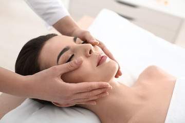 Fototapeta na wymiar Young woman enjoying facial massage in spa salon