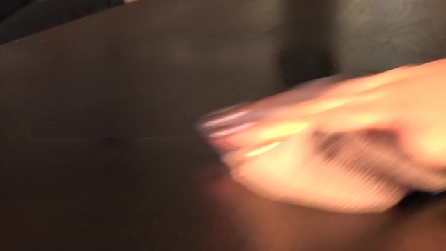 A woman cleans a table in a living room - closeup