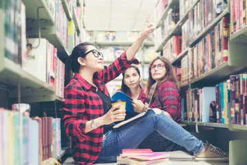 Group asian women in library reading something in a book and choosing a book in a library.  Education  Concept
