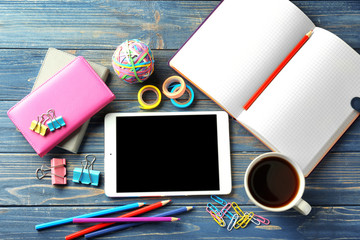 Tablet computer, cup of coffee and stationery on wooden background, flat lay. Workplace table composition
