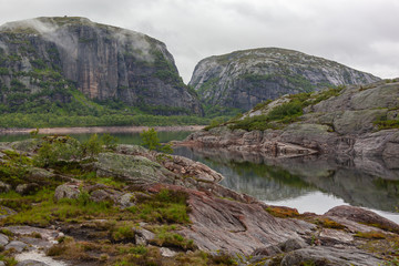 Meditative view of the calm mountain lake with moraine boulders on the shores,  Rogaland, Norway