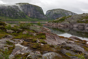 Fototapeta na wymiar Meditative view of the calm mountain lake with moraine boulders on the shores, Rogaland, Norway