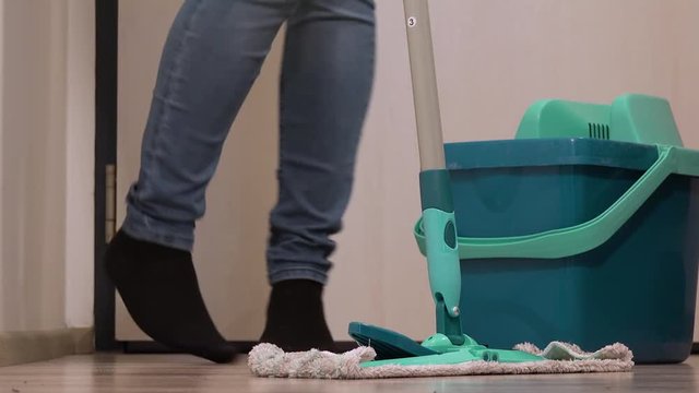 A woman dances while mopping a floor - closeup on the feet
