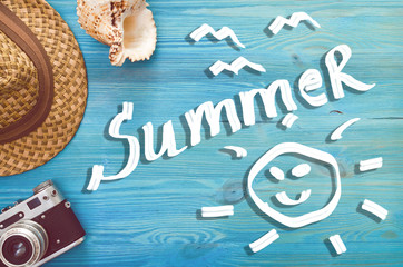 Summer background with copy space. Retro photo camera, seashell and hat on blue wooden background.