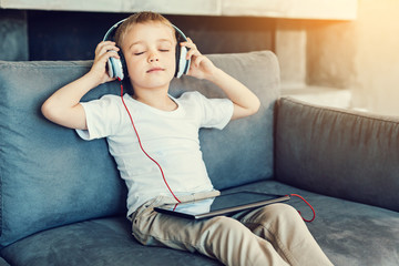 Relaxation. Pleasant little relaxed child sitting with his eyes closed while listening to the calm music