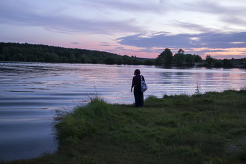 A girl enjoying summer sunset near lake. 