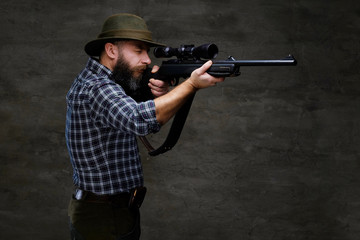 Hunter aiming a rifle in sight while preparing to make an accurate shot at the prey.