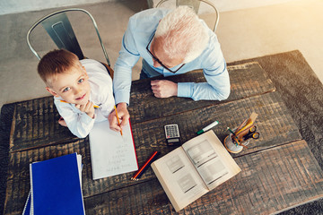 Fototapeta na wymiar Interesting homework. Attentive responsible senior man helping his grandchild to do his homework in mathematics