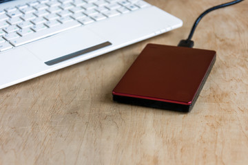 Modern storage, external hard drive and laptop keyboard  on wooden table background. Device for many data information.