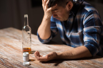 depression, drug abuse and addiction people concept - unhappy drunk man with bottle of alcohol and...