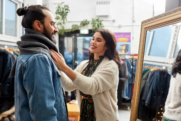 Fototapeta premium sale, shopping, fashion and people concept - couple choosing clothes at vintage clothing store