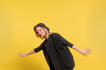 Portrait of a young beautiful woman with black hat in studio on a yellow background.