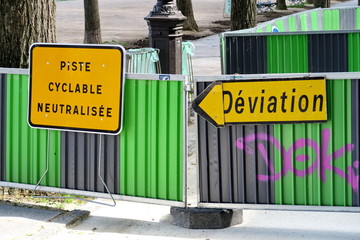 Piste cyclable neutralisée. Déviation. Panneaux routiers sur barrière.