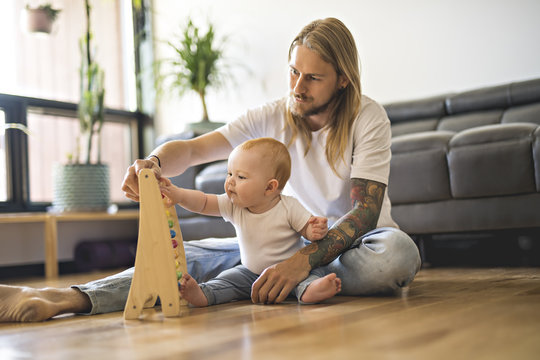 Cheerful Father Playing With His Baby Girl On Floor At Living Room