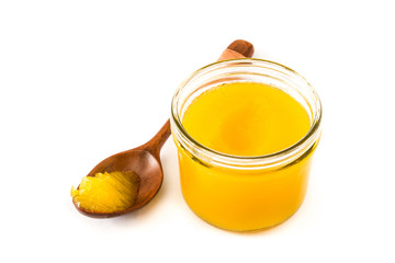Ghee or clarified butter in jar and wooden spoon isolated on white background