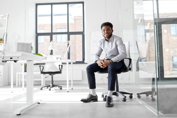 business and people concept - smiling african american businessman sitting on office chair