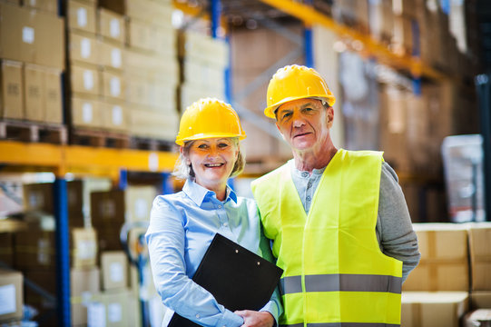 Senior woman manager and man worker standing in a warehouse.