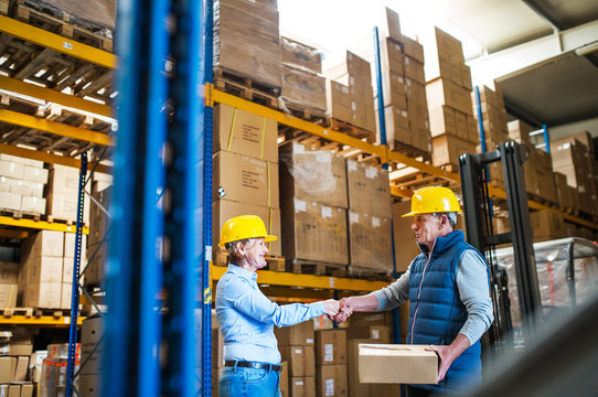 Senior woman managers or workers working in a warehouse, shaking hands.