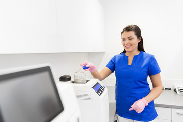 dentistry, medicine and healthcare concept - female dentist assistant arranging sterilization or...