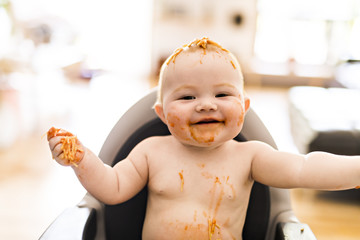 Little baby girl eating her spaghetti dinner and making a mess