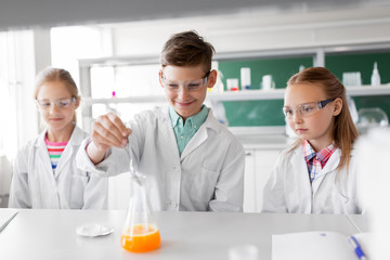 Fototapeta premium education, science, chemistry and children concept - kids or students with test tube making experiment at school laboratory