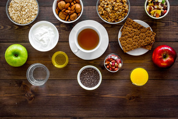 Set of products for healthy vegetarian breakfast. Fruits, oatmeal, yogurt, nuts, crispbreads, chia on dark wooden background top view space for text