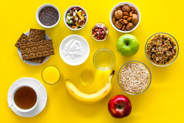 Layout of products for healthy and hearty breakfast. Fruits, oatmeal, yogurt, nuts, crispbreads, chia on yellow background top view copy space