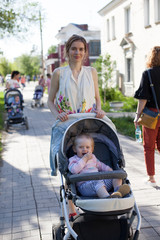 Mother walking in the street with her baby in stroller