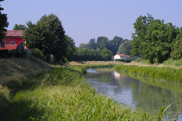 Obraz premium Rovigo, Italy - June, 5, 2018: house on the bank of a river in the vicinity of Rovigo, Italy