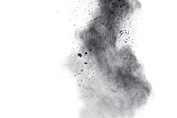 Black powder explosion. The particles of charcoal splatter on white background. Closeup of black...