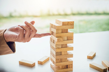 Alternative risk plan and strategy to growth profit in business, Young intelligent business woman playing the wood game, hands of executive placing wood block on the tower