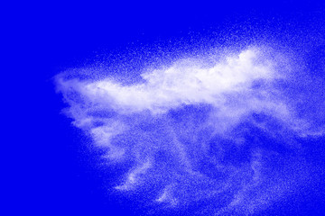 White powder dust explosion isolated on blue background.