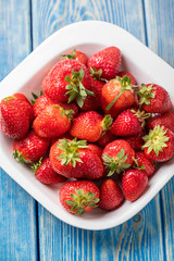 Ripe red strawberries in white bowl.