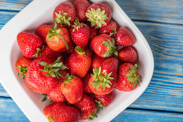 Ripe red strawberries in white bowl.