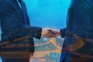 double exposure of businessman shaking hands with night cityscape for complete business deal together successful. teamwork concept. partnership and dealership concept and property real estate.