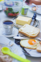 Cozy family breakfast by the sea: fried eggs, classic black coffee, cereal, juice, bacon on a plate and with vegetables.