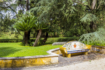 Fototapeta na wymiar View at Vatican Gardens with beautiful green lawns and trees and mosaic bench, Rome, Italy.