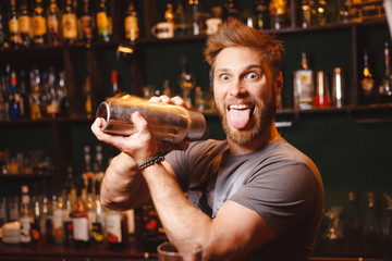 Joyful bartender mixes a cocktail in a shaker