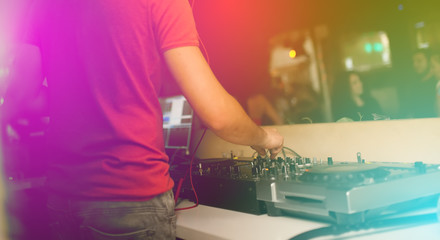 the hands of a young DJ operate a remote in a nightclub creating contemporary music
