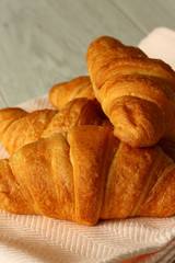 Croissants stacked on a plate with a pink tea towel on a grey wood background