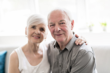 Affectionate attractive elderly couple sitting together on a couch